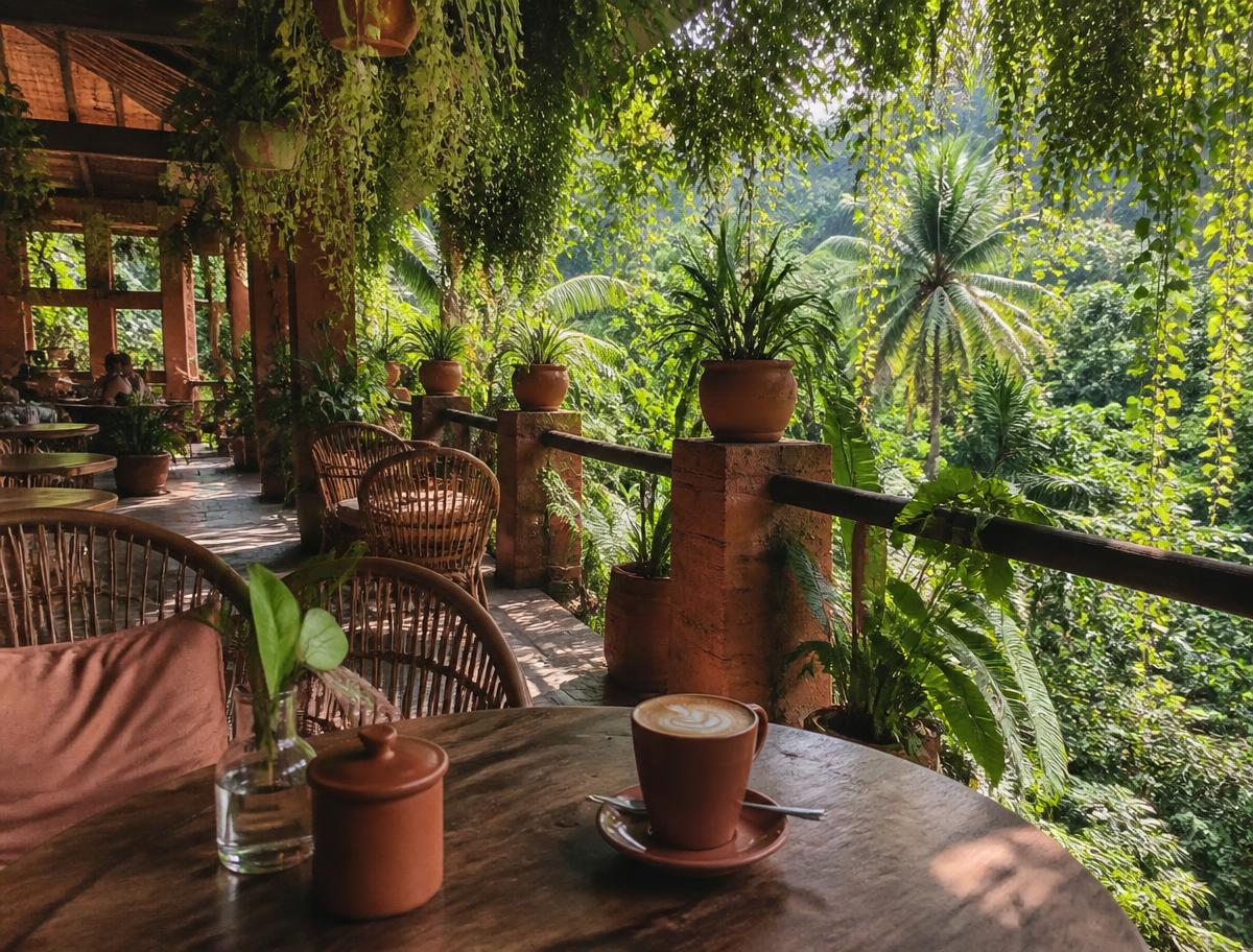Latte on a wooden table at an open-air jungle cafe in Bali